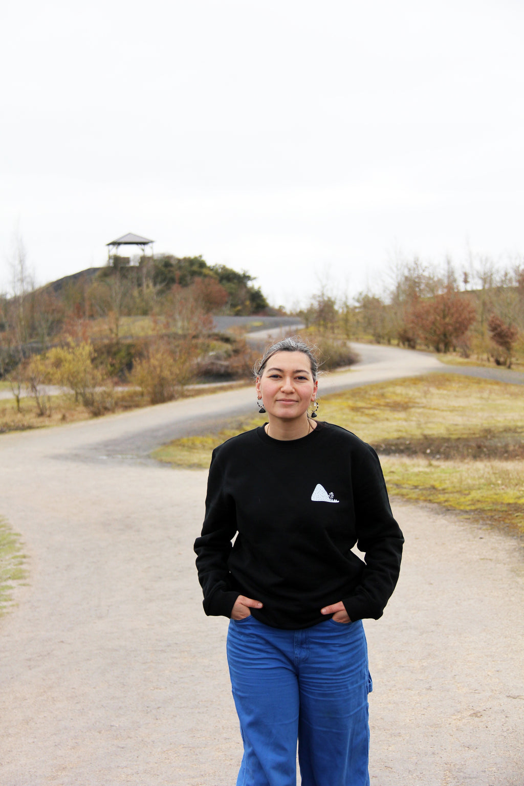 Sweatshirt unisexe noir Patrimoine minier porté de face en extérieur, coupe droite et visuel poitrine