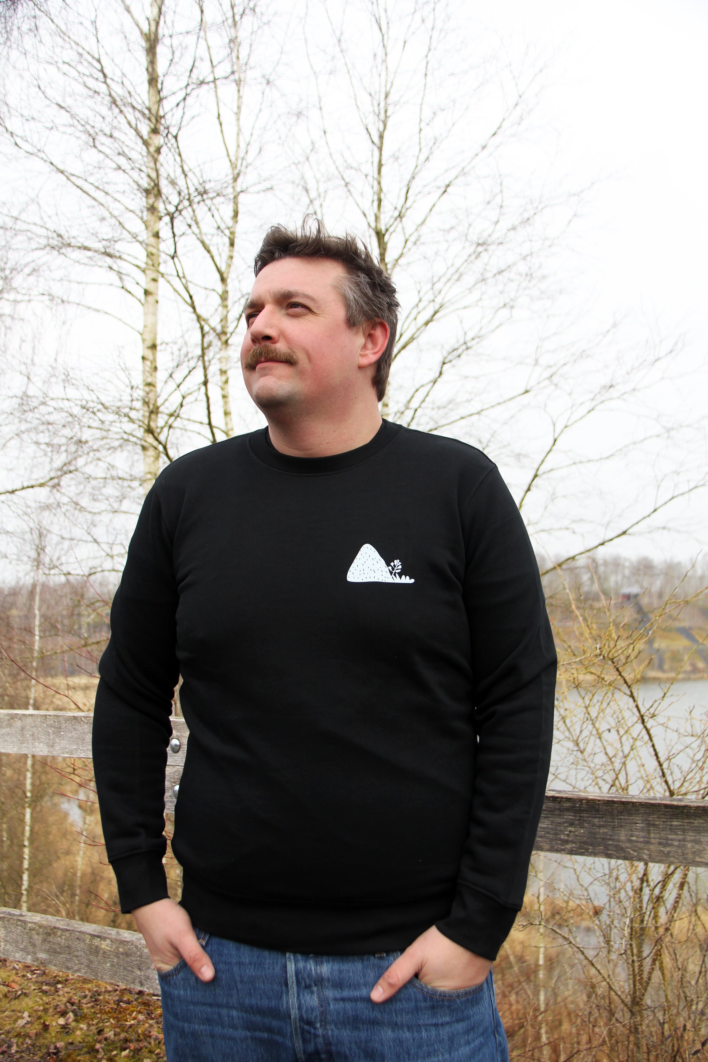 Sweatshirt unisexe noir Patrimoine minier porté de face, visuel terril blanc discret sur la poitrine