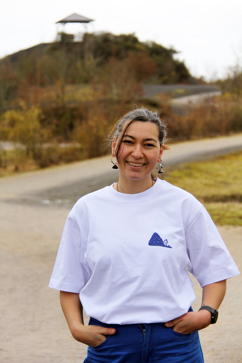 T-shirt unisexe blanc patrimoine minier porté de face, petit logo terril bleu sur la poitrine