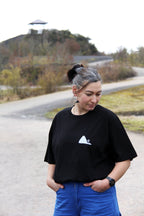 T-shirt unisexe noir patrimoine minier porté de face, petit logo terril blanc sur la poitrine